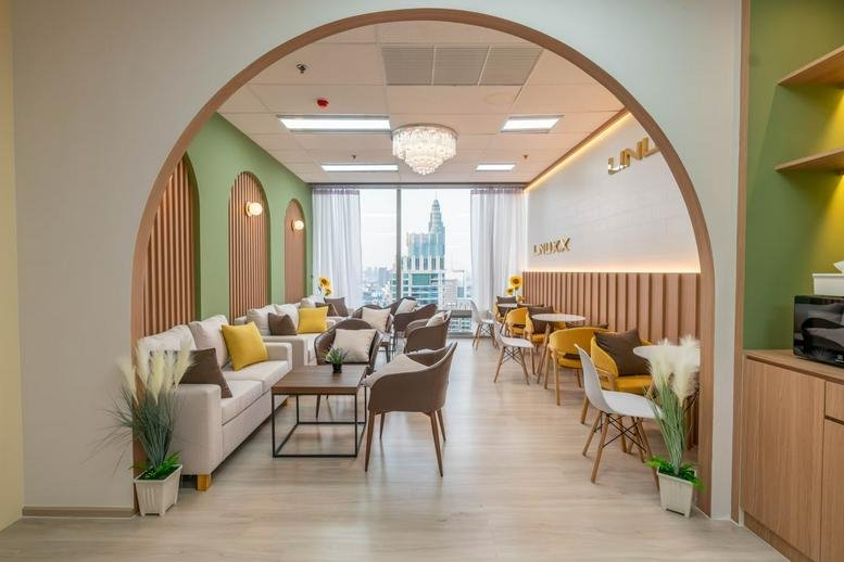 Professional reception lobby with a marble branded wall, grey armchairs, and a bright, open floor plan.