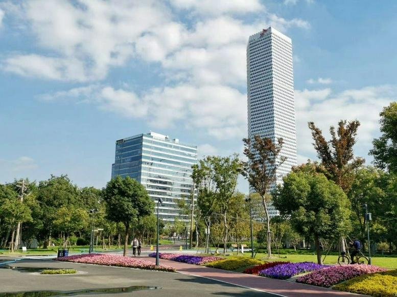 Exterior view of the towering glass facade of Building 1 at Global Metropolis Plaza next to a lush park.