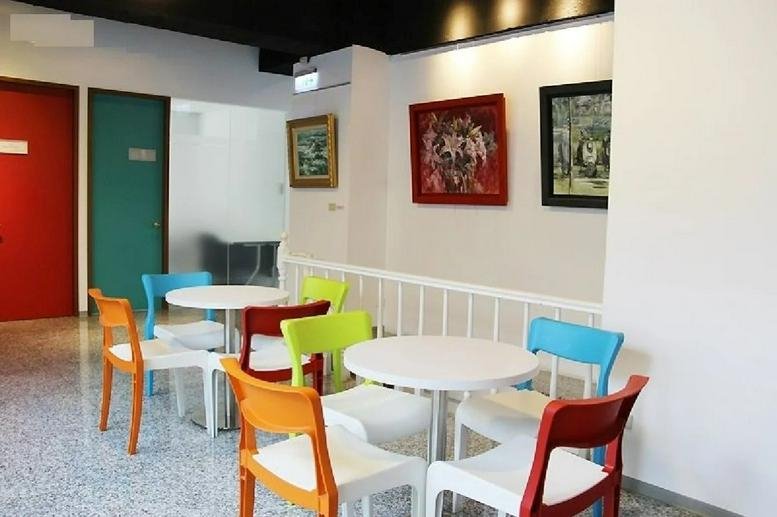 Colorful breakout area with white cafe tables and vibrant blue, orange, and lime green chairs.