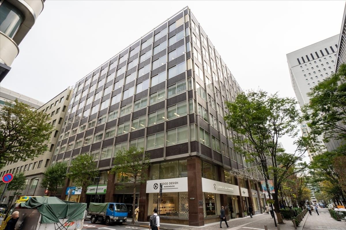 Exterior view of the Marunouchi Shin Kokusai Building featuring a glass facade and street-level shops.