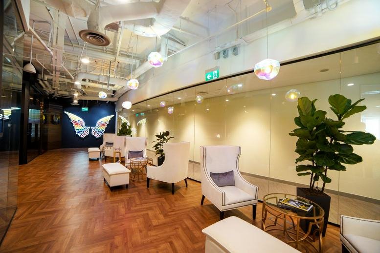 Spacious reception lounge at Duo Tower featuring white wingback chairs and warm herringbone wood floors.