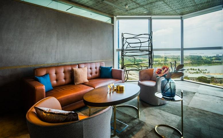 Bright communal lounge at Centennial Tower with leather sofa and floor-to-ceiling windows showing water views.