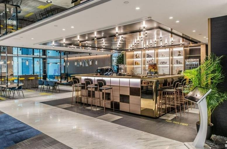 Spacious communal bar and lounge area with warm lighting and indoor plants.