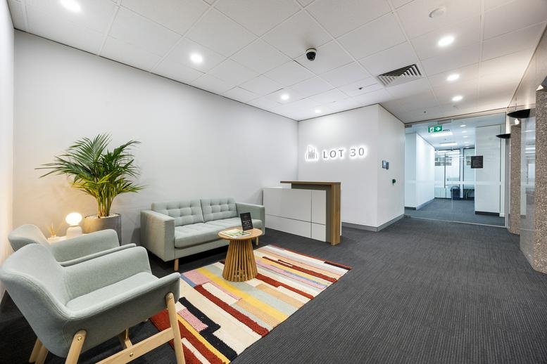 Modern reception lobby with colorful rug and grey seating at 30 Currie Street, Level 8.