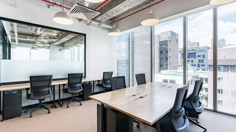 Open-plan workspace with multiple desks and city views.
