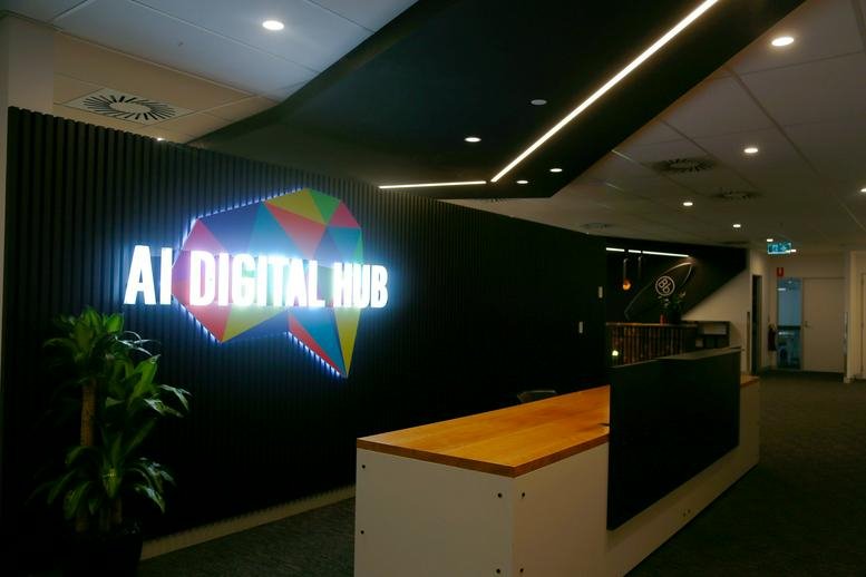 Modern reception area at 300 Queen Street, Brisbane featuring a backlit AI Digital Hub logo and wooden front desk.