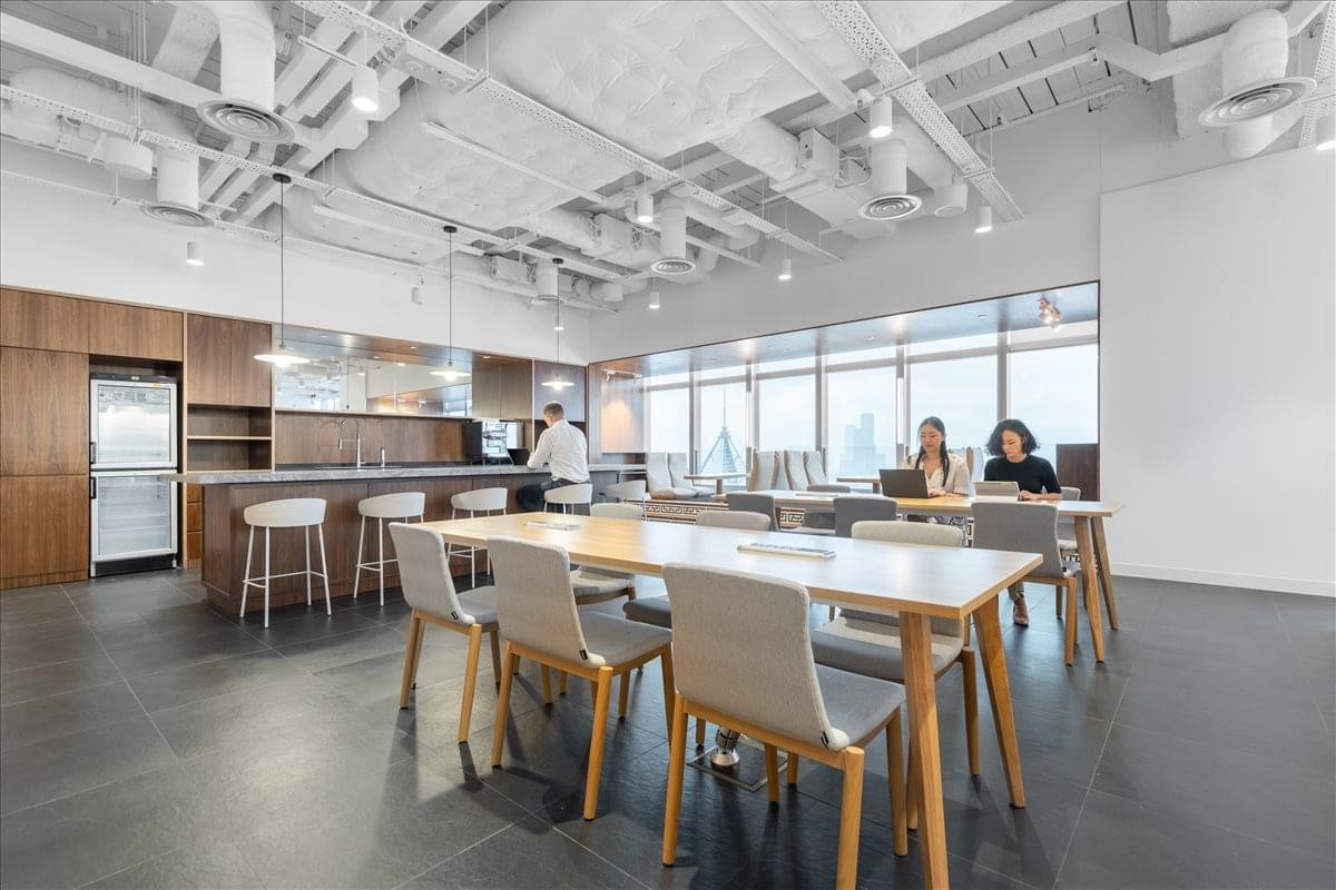 Spacious communal kitchen and dining area at Hysan Place with modern stools and industrial ceiling.