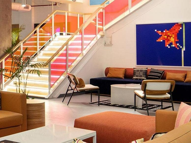 Spacious communal lounge with a vibrant staircase and modern art at 32nd Milestone, 4th Floor, The Galaxy Hotel.