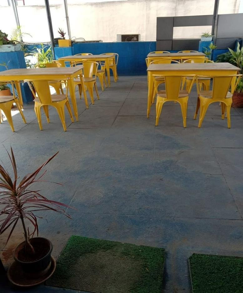 Rooftop common area at 343, 9th Main Road with yellow tables and chairs and potted plants.