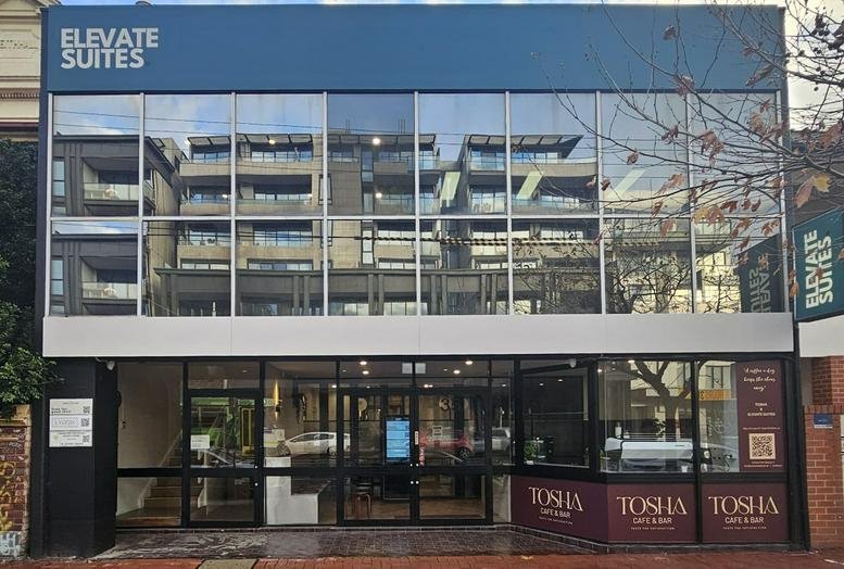 Exterior view of the glass-facade building for Elevate Suites at 35 Lygon Street.