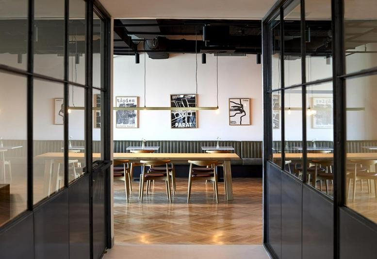 Spacious communal dining area at 380 St Kilda Road, Level 14 with a long wooden table and designer lighting.