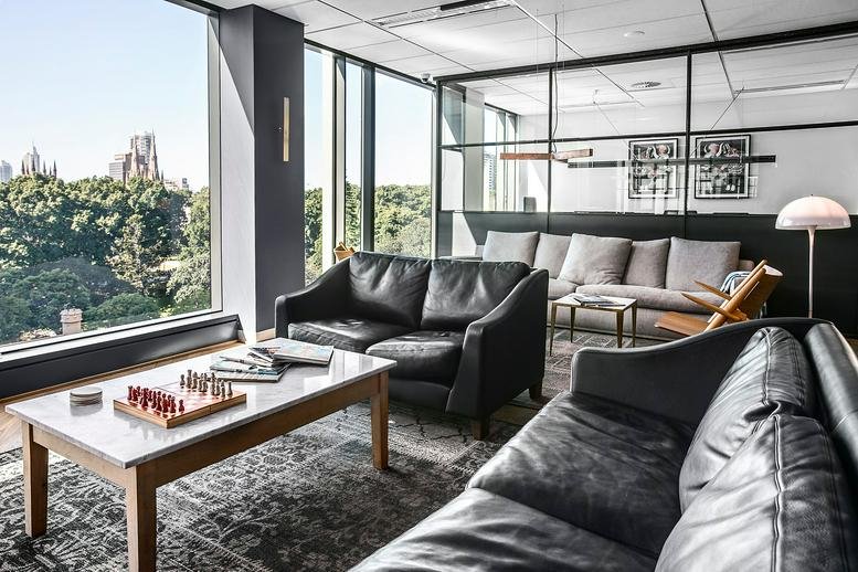 Sunlit lounge area with leather sofas and views of city parkland.