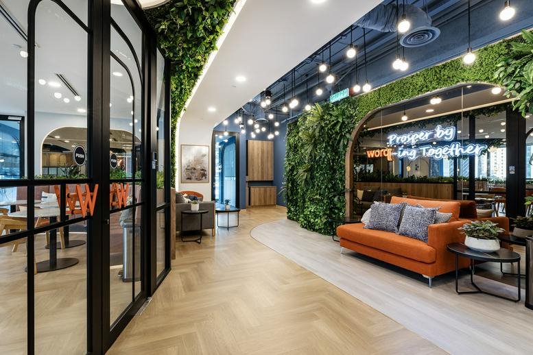 Lobby area at Integra Tower with vibrant greenery walls and a modern orange sofa.