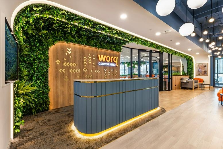 Reception desk at Integra Tower with wooden slats and greenery.