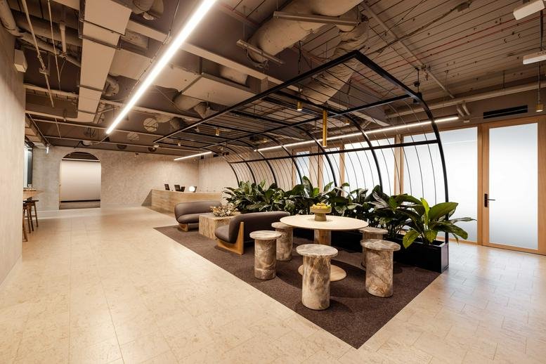 Spacious reception lounge at 385 Bourke Street with marble seating, plants, and an architectural arch.