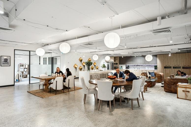 Large open-plan coworking space with various seating options and spherical pendant lights.