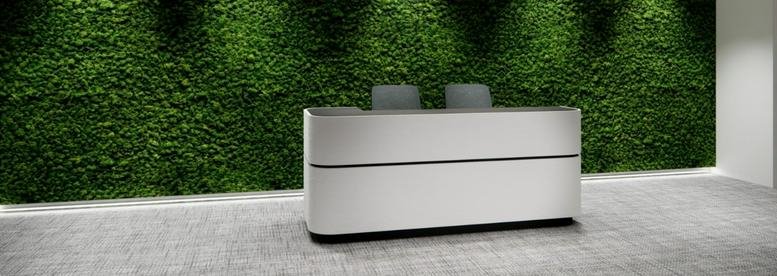 Reception area at Dah Sing Financial Centre with a sleek white desk against a vibrant green moss wall.