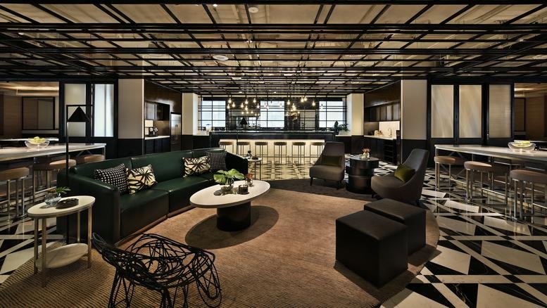 Spacious communal lounge at Ngee Ann City Tower B with dark green velvet sofas and a stylish patterned floor.
