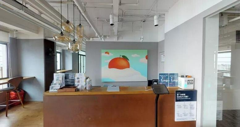 Reception area at 3F-7F, The House, Xintiandi Xinli with a wooden desk and a colorful peach painting.