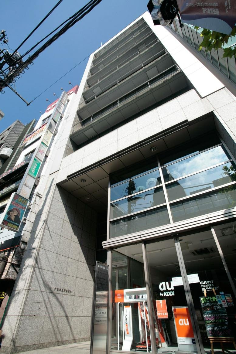 Exterior view of the Roppongi-Mikawadai Building 7F featuring a modern facade and street-level shop.