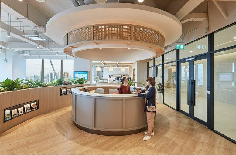 Circular wooden reception desk under a large tiered light fixture at Floor 37, 40, Ploenchit Road, Lumpini.