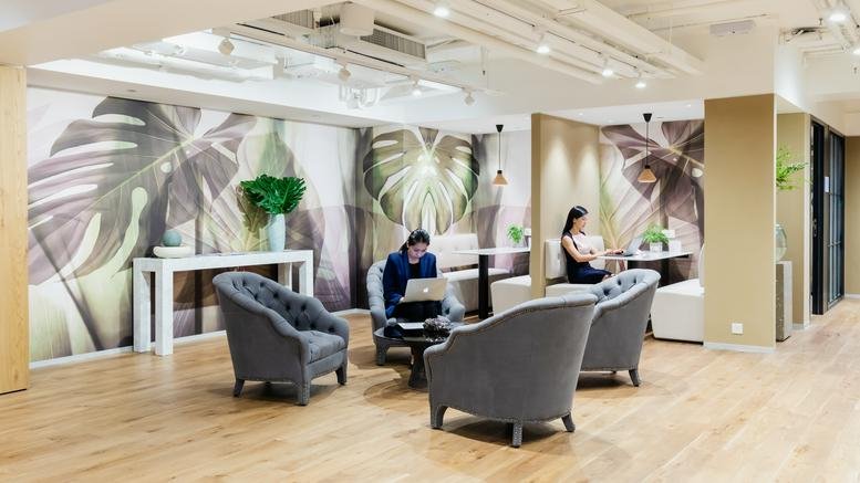 Spacious lounge at Nexxus Building with botanical wallpaper, velvet armchairs, and warm wooden flooring.