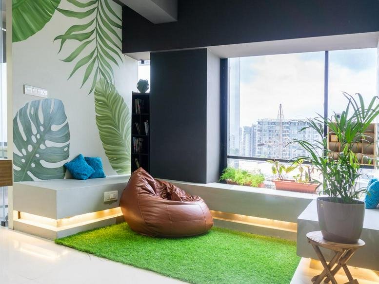 Bright breakout area at Solarium Business Center with a bean bag, artificial turf, and leaf-motif wall art.