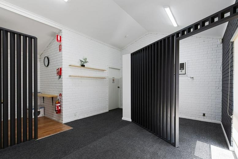 Spacious reception area with dark grey carpeting and modern black slatted partitions.