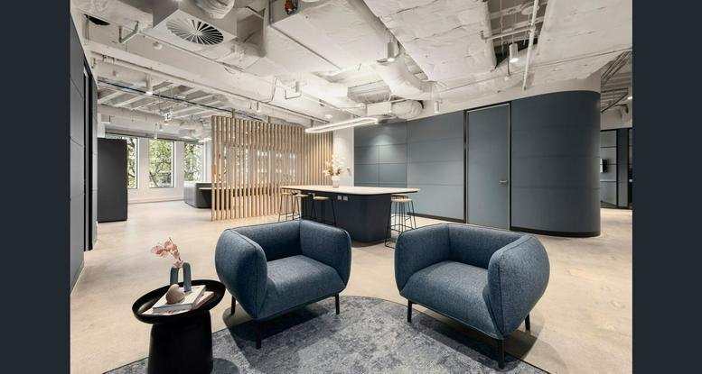 Expansive building lobby at 440 Collins Street featuring red velvet armchairs and digital screens.