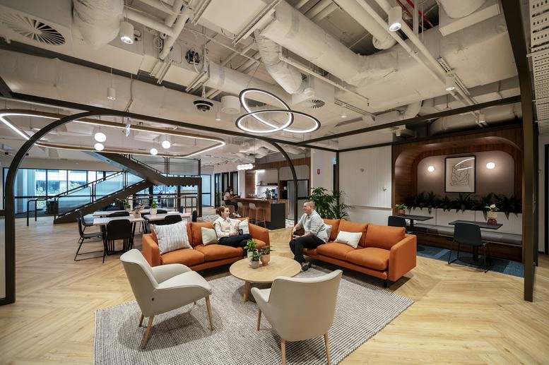 Spacious communal lounge at 447 Collins Street, Levels 4-5, Collins Arch, Melbourne with orange sofas and wood floors.