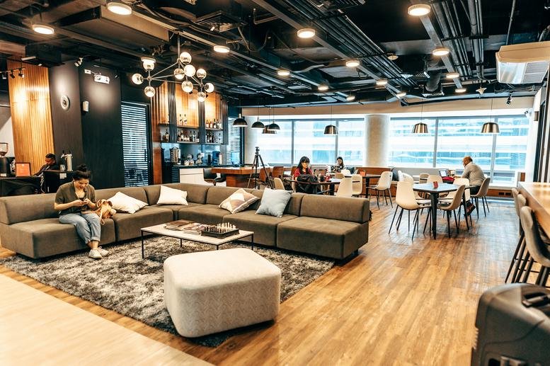 Spacious communal lounge and coworking area at 5/F Phinma Plaza with warm lighting and wooden floors.
