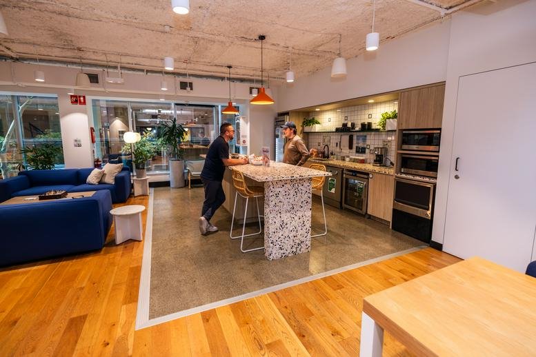 Social kitchen and breakout space at WOTSO North Sydney, 50 Miller Street with a marble island and blue sofa.