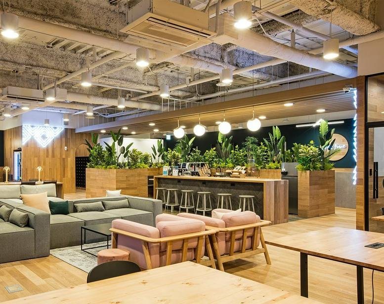 Spacious communal lounge at 501, Teheran-ro, Samsung 2, Seoul featuring warm wood tones, plants, and sofa seating.