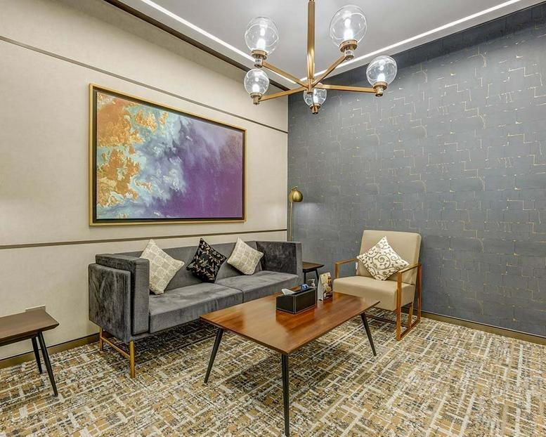 Modern reception lounge at 502, Raheja Titanium, featuring a velvet sofa and abstract painting.