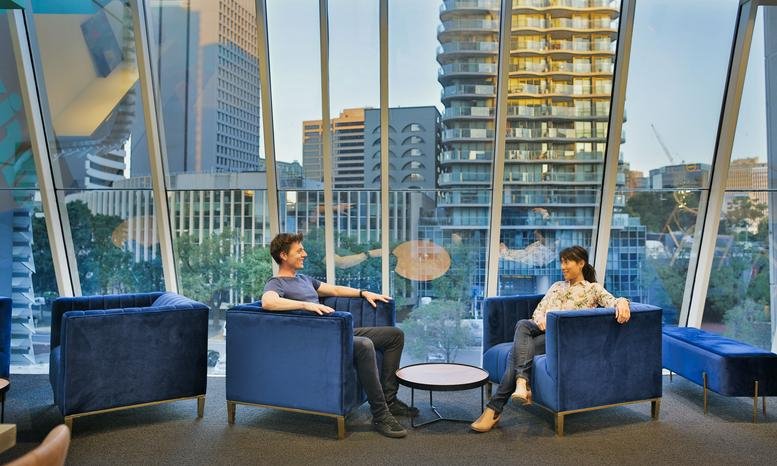 Lounge area at Levels 2 & 3, 52 Albert Road with blue velvet armchairs and floor-to-ceiling city views.