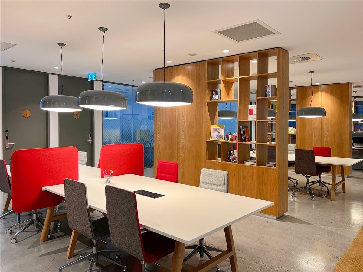 Spacious coworking area at 525 Collins Street, Rialto M2, West Podium with white tables and vibrant red chairs.