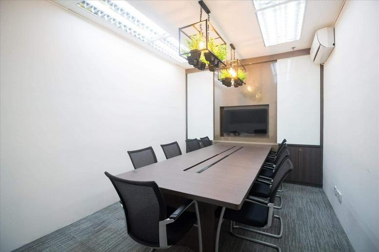 A professional meeting room at 54, Genting Lane with a dark wood table and industrial pendant lighting.