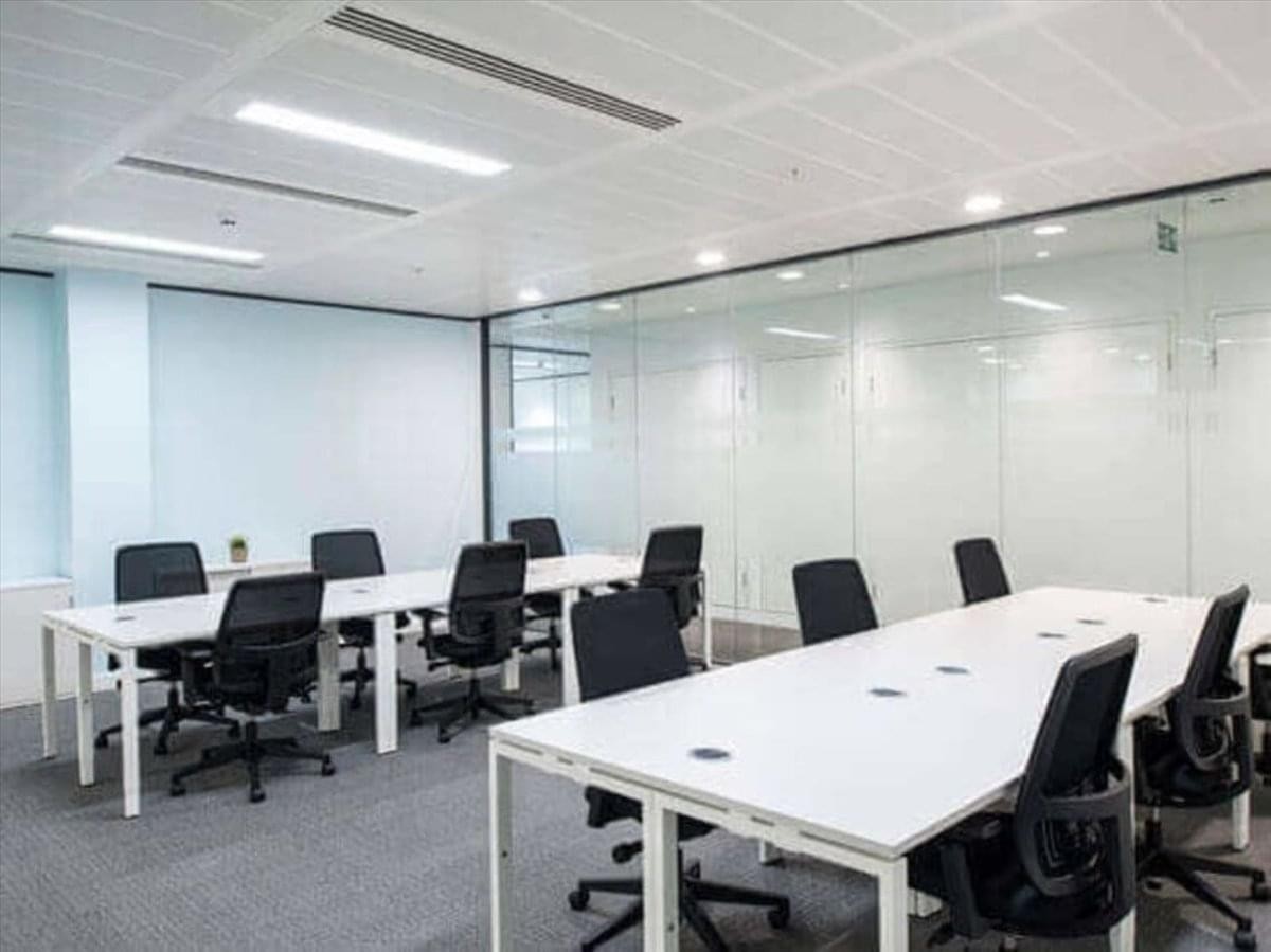 Open-plan office area at 546 Ratchadaphisek Road featuring long white workstations and glass walls.