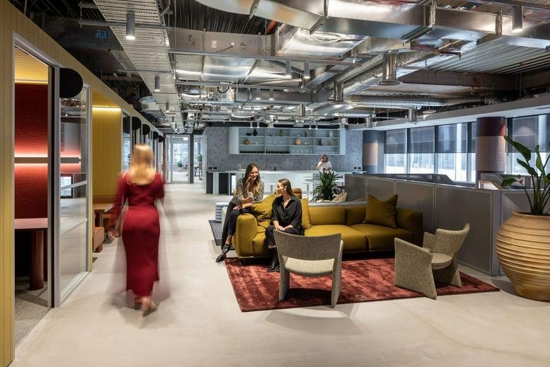 Spacious communal lounge at 550 Bourke Street, Level 10 & 11 with warm lighting and a modern industrial ceiling.