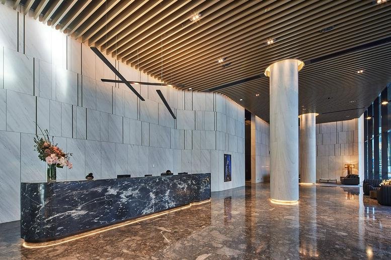 Spacious reception lobby featuring a dark marble desk and slatted timber ceiling.