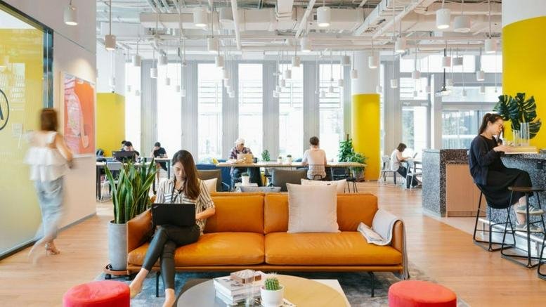 Spacious communal lounge at Huihuang Time Building with orange sofa, yellow pillars, and abundant natural light.