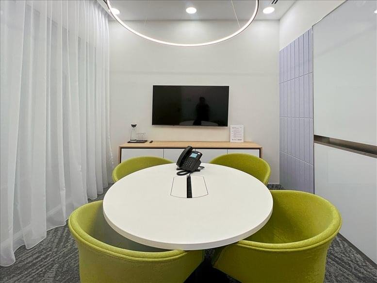 Small private meeting room featuring lime green tub chairs and a circular white pedestal table.