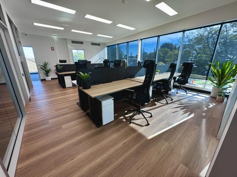 Bright, open-plan workspace at 62 Queen Street with modern desks, ergonomic chairs, and large windows.