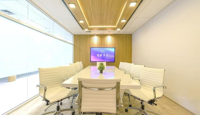 Executive boardroom at Emporium Tower with a large white table and wood-paneled feature wall.