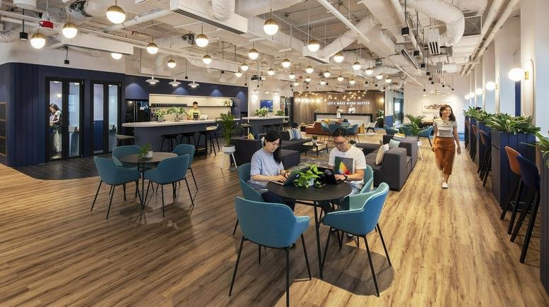 Spacious coworking area at OCBC Centre East with warm wood floors and vibrant blue seating.