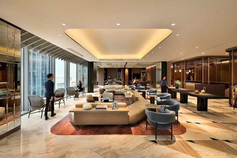 Main lounge area at 63 Robinson Road featuring curved sofas, designer armchairs, and a bright recessed ceiling.