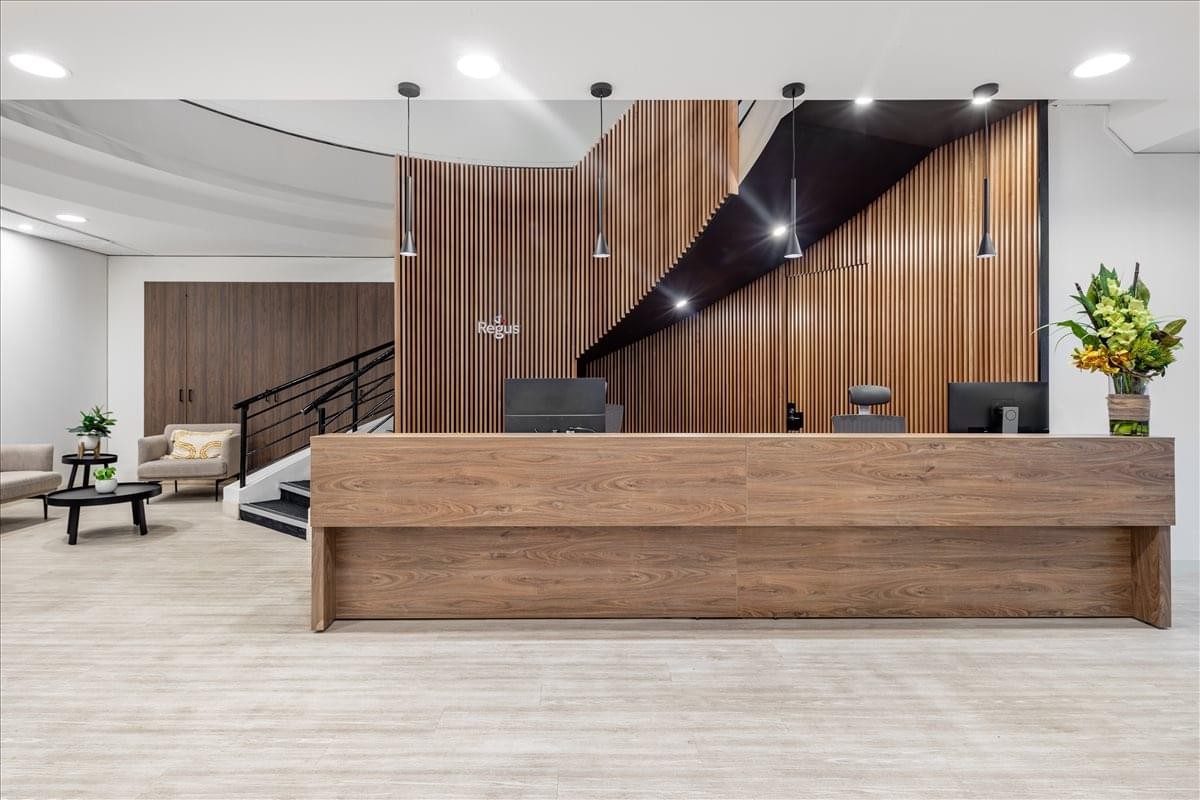 Spacious reception area with a long wooden desk and a staircase backdrop.