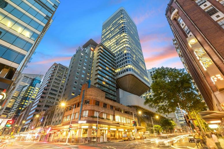Evening exterior view of the modern high-rise office building against a sunset sky.