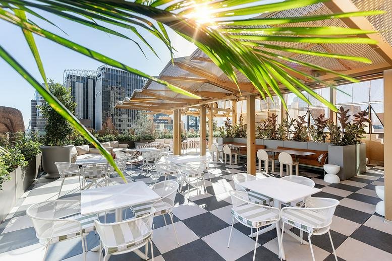 Sunny rooftop terrace at 66 King Street, Sydney with white furniture and checkered flooring.