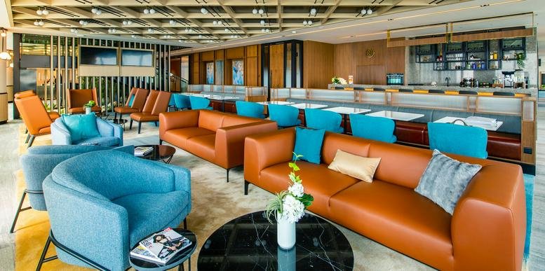 Spacious communal lounge with orange leather sofas and blue armchairs at Global Metropolis Building.